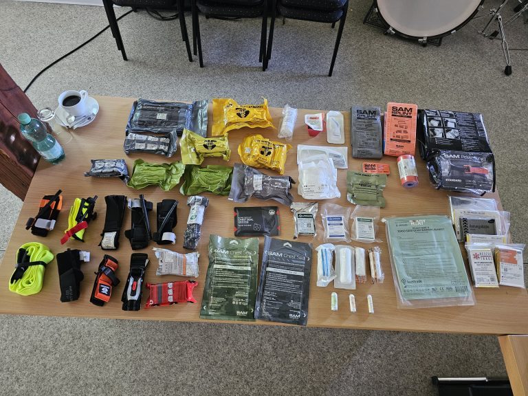 Ausrüstung auf einem Tisch ausgelegt: Tourniquets, Chest Seals, SAM-Schienen, Verbandmaterial und Rettungsdecken