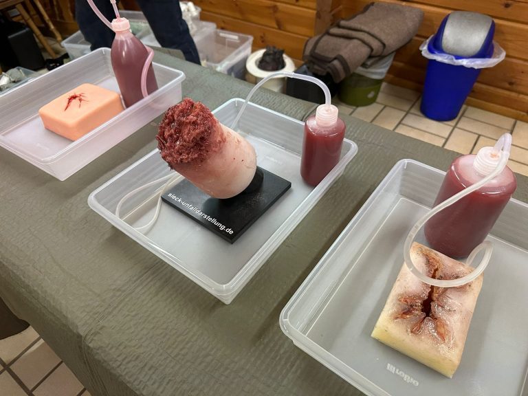 Drei Wundmodelle mit Kunstblut in Übungswannen, bereit für das Training